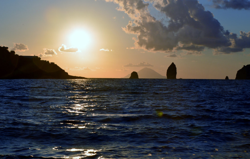 I Faraglioni tra l'isola di Vulcano e quella di Lipari al tramonto, in controluce. Sullo sfondo la "piramide" dell'Isola di Stromboli
