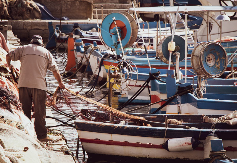Un pescatore raccoglie le reti nel porto di Mondello a Palermo