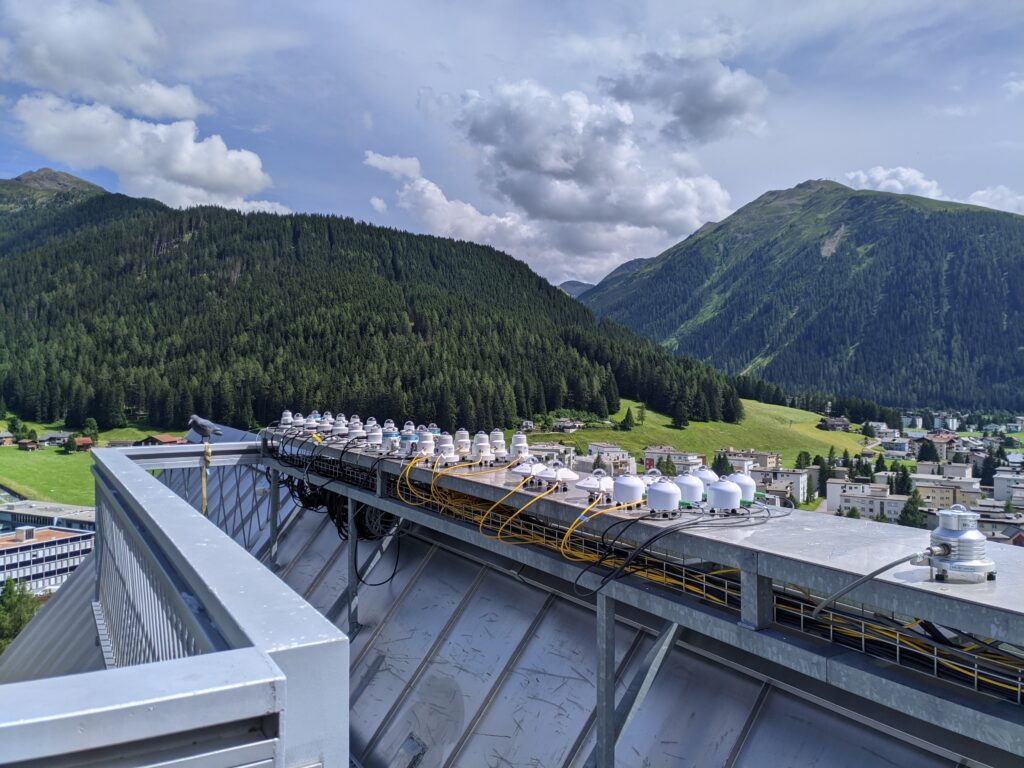 Il sito scelto per l’interconfronto nazionale è stato la città di Davos (1560 m s.l.m.), nella suggestiva cornice delle Alpi svizzere, dove è presente il centro mondiale radiazioni. Gli strumenti sono stati disposti uno vicino all’altro (parte bassa della figura) e le misure di un intero mese sono poi state confrontate.
(photo credit G. Hülsen, PMOD/WRC)